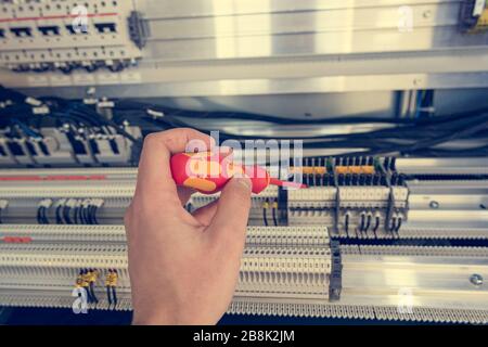 Electrical engineer checking electric cubicle and fixing connector strips. Stock Photo