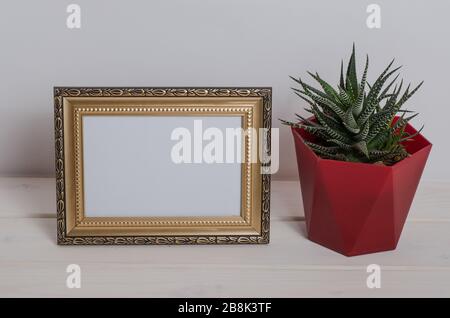 Mock up frame on a white wooden table with cactus in the room. Desktop. Stock Photo