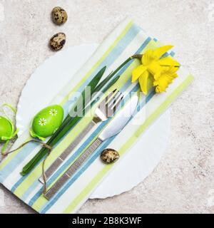 Beautiful festive or Easter table setting with spring flowers and eggs on light textured background. Top view with copy space. Stock Photo