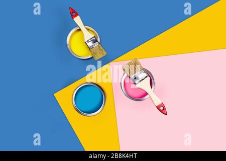 Renovation of the apartment or house for more fruitful work at home. Paint cans and brushes on a tricolor background. Stock Photo