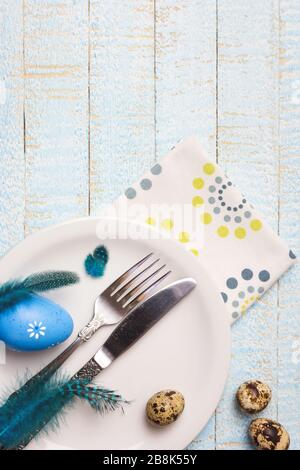 Beautiful festive or Easter table setting with eggs and feathers on light wooden background. Top view with copy space. Stock Photo