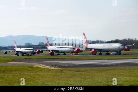 Prestwick, Scotland, UK. 22 March, 2020. Three Airbus A340 aircraft owned by Virgin Atlantic parked and in storage at Glasgow Prestwick airport. Many airlines have parked surplus aircraft at the airport and at others across the UK because passenger numbers and flights have plummeted during the Coronavirus pandemic. Iain Masterton/Alamy Live News. Stock Photo