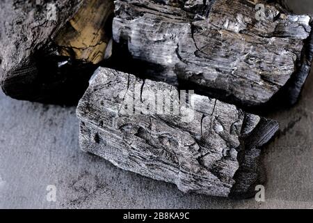 Large black coals from a tree close-up. Charcoal for barbecue on a black background. Stock Photo