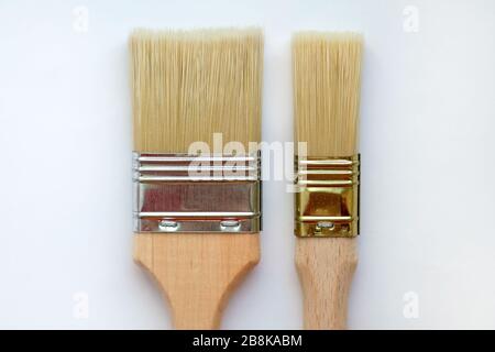 A wide paint brush and a small one on a white background top view. Paint brushes of different lengths and thicknesses. Two flat tassels with wooden ha Stock Photo