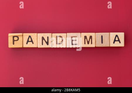 The word pandemic on a red background top view. Wooden cubes with letters. The spread of the virus. Stock Photo