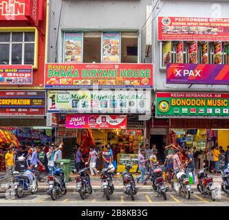 Streetscape row of shophouses parked motorcycles and Indian men walking along Jalan Tun Tan Siew Sin Chinatown Kuala Lumpur Malaysia. Stock Photo