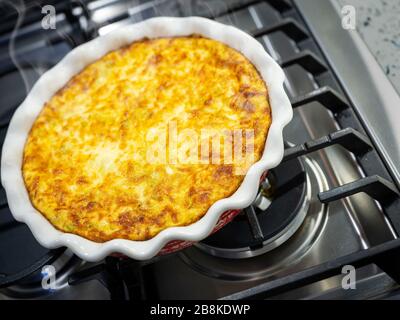 Quiche with steam rising cooling on stove top, USA Stock Photo