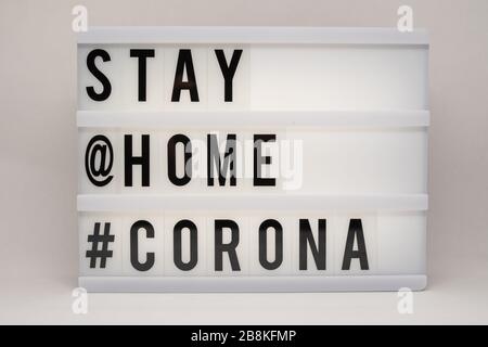 is written on an illuminated panel with black letters: Stay at home #Corona Stock Photo