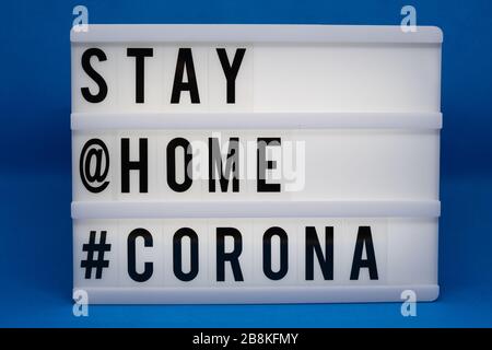 is written on an illuminated panel with black letters: Stay at home #Corona Stock Photo