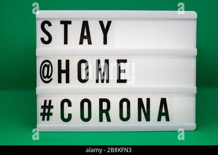 is written on an illuminated panel with black letters: Stay at home #Corona Stock Photo