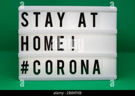 is written on an illuminated panel with black letters: Stay at home #Corona Stock Photo