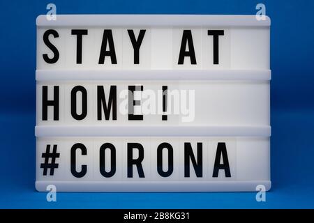 is written on an illuminated panel with black letters: Stay at home #Corona Stock Photo