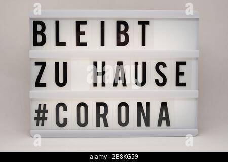 is written on an illuminated panel with black letters: Stay at home #Corona Stock Photo