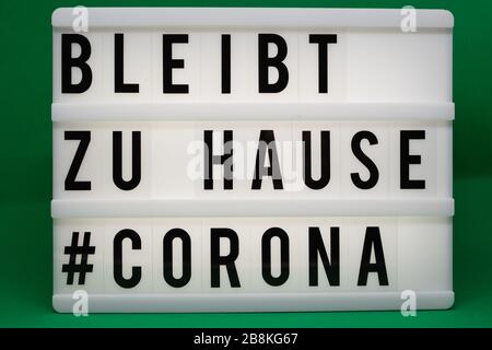 is written on an illuminated panel with black letters: Stay at home #Corona Stock Photo