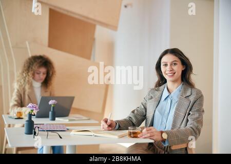 Portrait of smiling female student smiling at camera while studying in college cafe, copy space Stock Photo