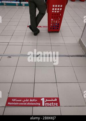 Maintain social distancing corona virus disease (COVID-19)  warning sigh in Arabic and English on the floor of department store. New Normal Stock Photo