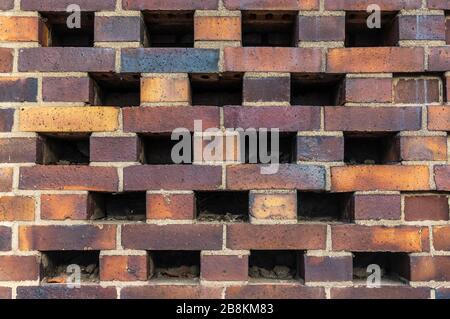 Building wall made of dark, yellow to brownish clinker bricks with various alternating patterns. The stones are offset in rows, turned, indented or om Stock Photo
