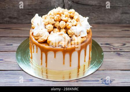 Homemade salted caramel cake with caramel sauce and caramel popcorn on wooden background Stock Photo
