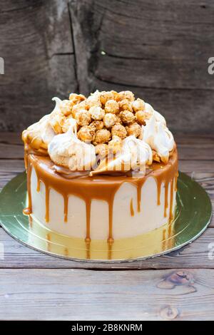 Homemade salted caramel cake with caramel sauce and caramel popcorn on wooden background Stock Photo