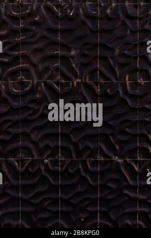 Tiles black with sculpted raised surface like shapes of sand dunes or desert formations almost seamless on a facade, detail Stock Photo