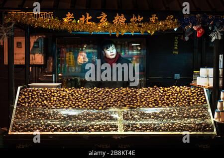 WANGFUJING NIGHT MARKET, BEIJING - DEC 25, 2013 - Young chestnut seller at Wangfujing snack street, Beijing Stock Photo