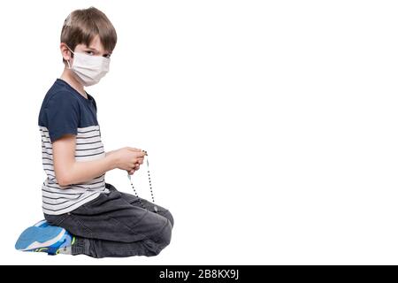 Little boy with face mask praying and holding rosary, isolated on white background Stock Photo