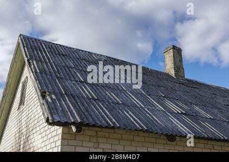 Brick house roof covered with asbestos slate Stock Photo
