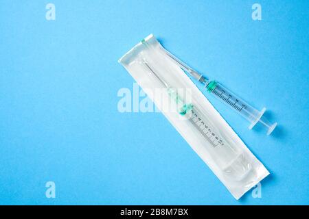 Two plastic disposable medical syringes open and package lie on blue background. Pharmaceutical Concept Health care and medicine. free Copy space Stock Photo