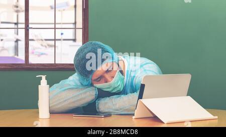 Tired exhausted doctor after long shift fighting against Coronavirus (2019-nCoV) falls asleep at hospital next to emergency salon - global pandemic Stock Photo