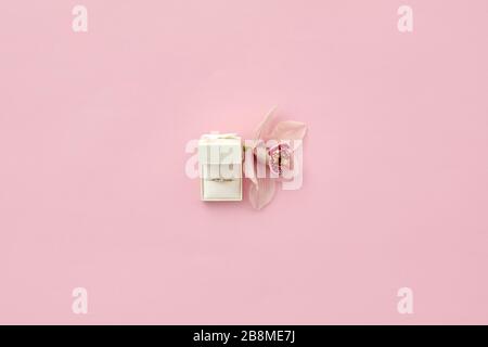 Pink box with engagement ring and orchid flower on pink background, top view. Space for text Stock Photo