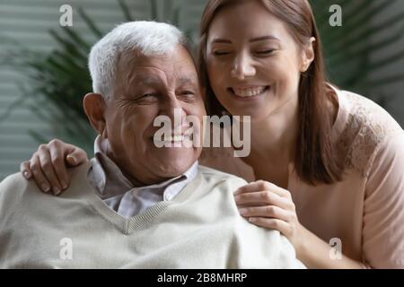 Closeup image candid grown up daughter hugs elderly father Stock Photo