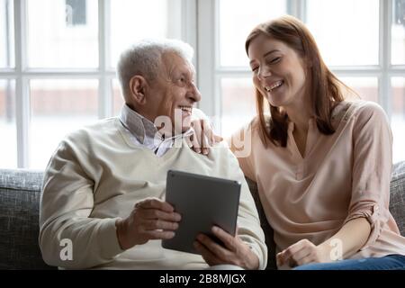 Grownup daughter her old father spend time together using tablet Stock Photo