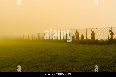 Trabzon / Turkey - August 07 2019: Silhouette of people walk behind the wire in a cold day under fog Stock Photo