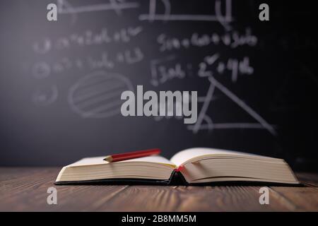 Open books on the table against black board. Stock Photo