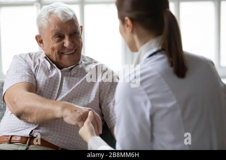 Nurse in uniform talking during day visit to elderly patient Stock Photo
