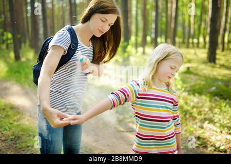 Mother applying insect repellent to her daughter before forest hike beautiful summer day. Protecting children from biting insects at summer. Using bug Stock Photo