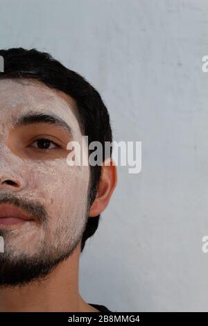 portrait of young Hispanic man with a beard wearing a hydrating mask on a white background Stock Photo