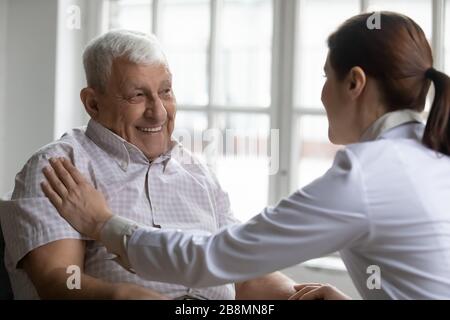 Old man patient and careful nurse communication indoors Stock Photo