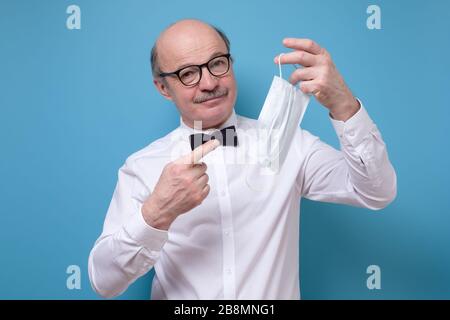 Young caucasian man with mustache pointing on a medical mask. Stock Photo