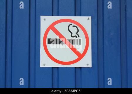 On the blue wall there is a white sign with an inscription prohibiting smoking. The concept of health and prohibition. Stock Photo