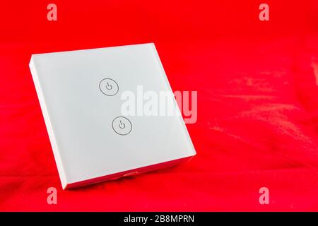 Smart Wi-Fi switch with support for control via mobile  phone application. SHot on red background Stock Photo
