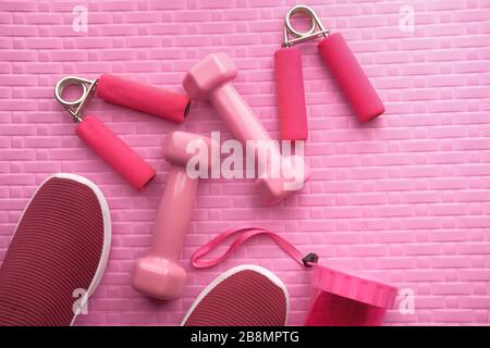 Yoga mat with sport shoes and dumbbells on pink background Stock Photo