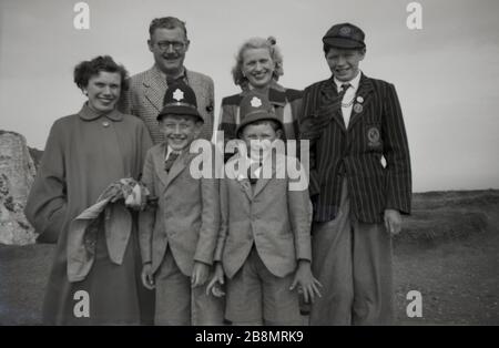1952, historical, family photo, mum, dad and three boys in their school uniform, with the two youngest having fun wearing their imitation or fancy dress police helmets, England, UK. Stock Photo