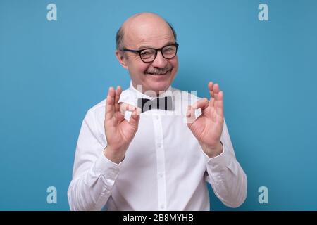 Caucasian man in white shirt smiling on camera with alright ok sign Stock Photo