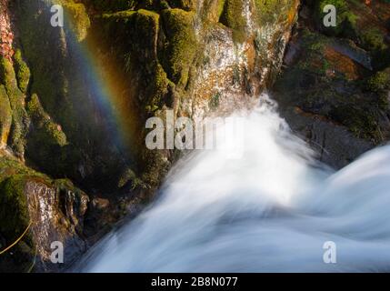 a photo taken from the top of a waterfall, revealing a rainbow down the lower arias of it. this was taken with a slow shutter speed to show the flow Stock Photo