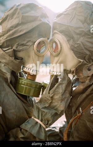 Portrait of couple in love in NBC protective suits and gas masks. Concept of preventive measures and protection for coronavirus COVID 19 pandemic and Stock Photo