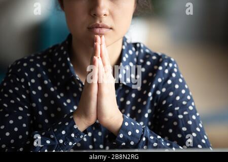 Close up mindful Indian woman putting hands in prayer Stock Photo