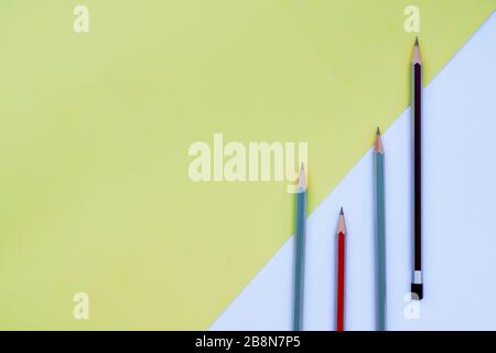 Four wood pencil crayons of different color isolated on a colorful paper background Stock Photo