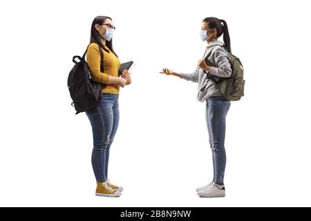 Young female students wearing protective medical masks and having a conversation isolated on white background Stock Photo