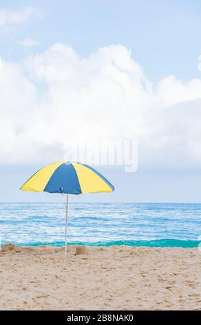 Beach umbrella in beautiful scenery with sand, blue sea and cloudy sky in Trindade, Paraty, Brazil. Paraty is located on the Costa Verde (Green Coast) Stock Photo